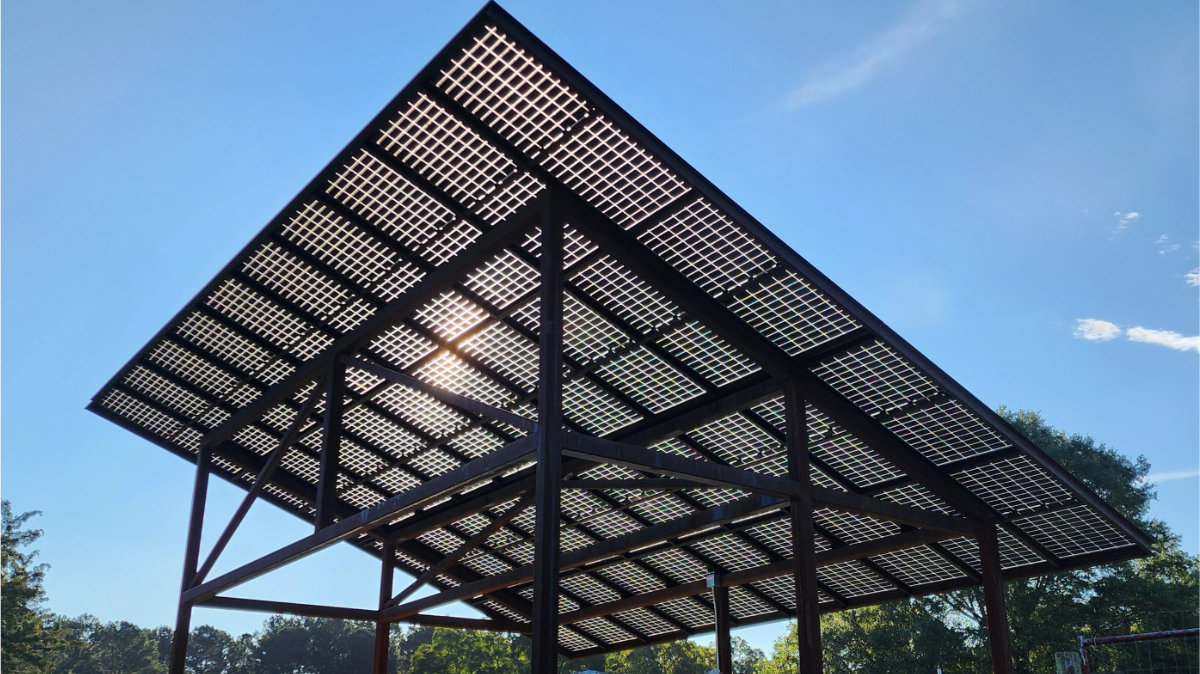 Solar carport with rooftop solar panels providing shade and generating electricity to charge an electric vehicle.